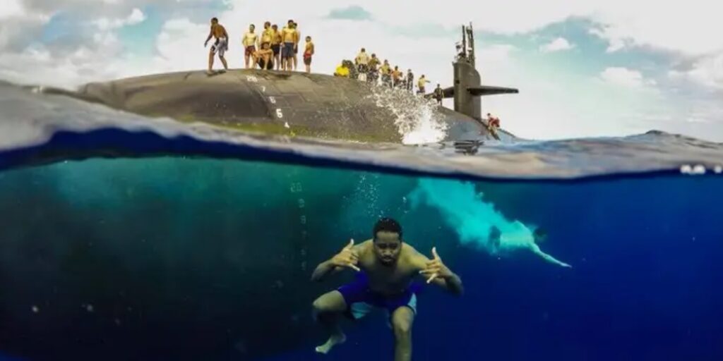 Sailors swimming next to submarine. Submechanophobia. Submarine underwater photo.